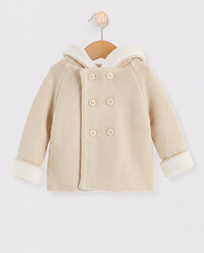 Beige children's coat with white trim on a wooden hanger against a light gray background
