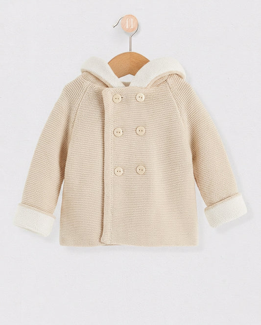 Beige children's coat with white trim on a wooden hanger against a light gray background