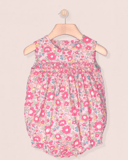 Floral-patterned baby dress on a hanger against a beige background