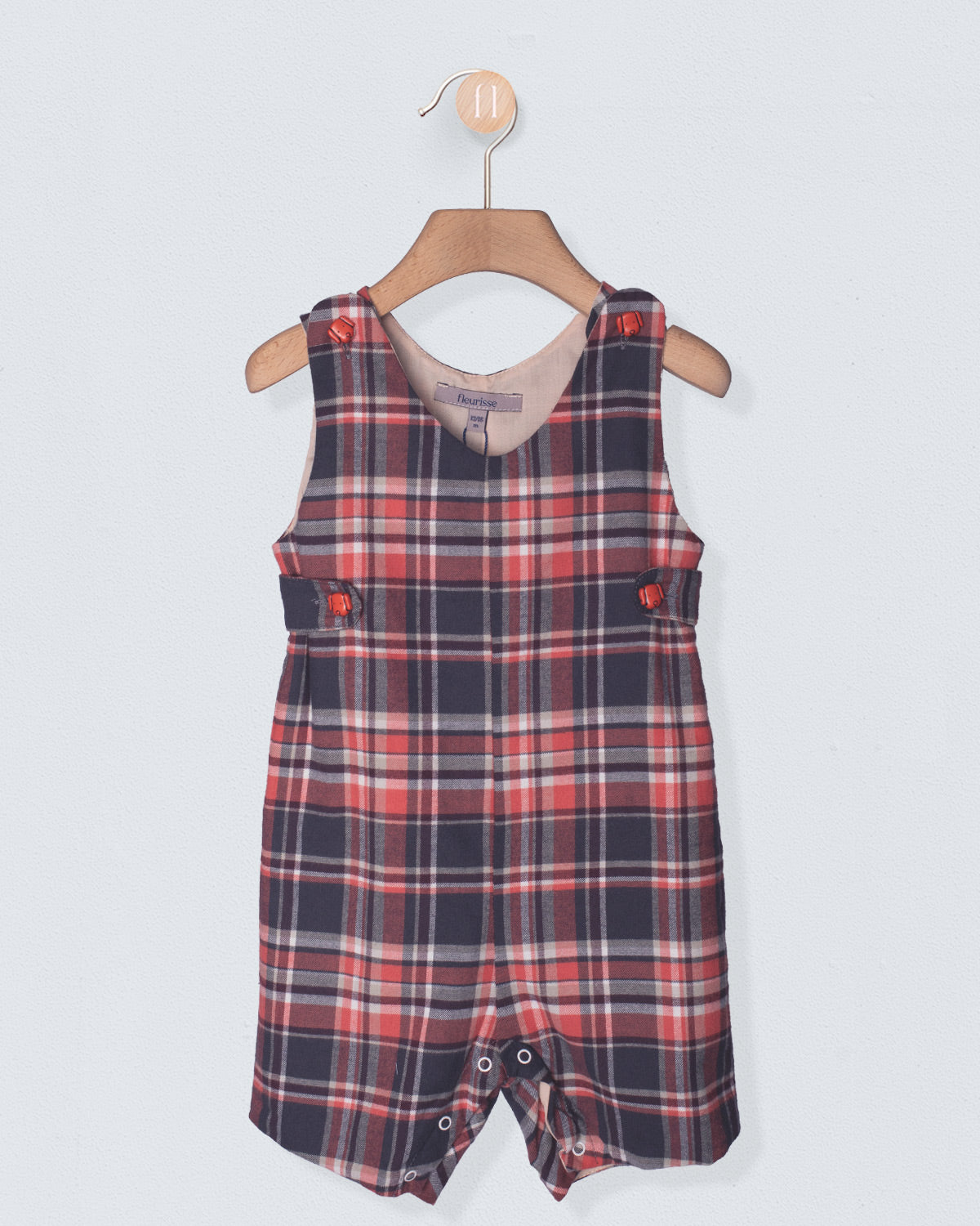 Plaid romper on a hanger against a light gray background