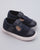 Pair of navy blue canvas toddler sneakers with white rubber soles, navy leather toe caps, and velcro straps, placed at a slight angle on a gray background.