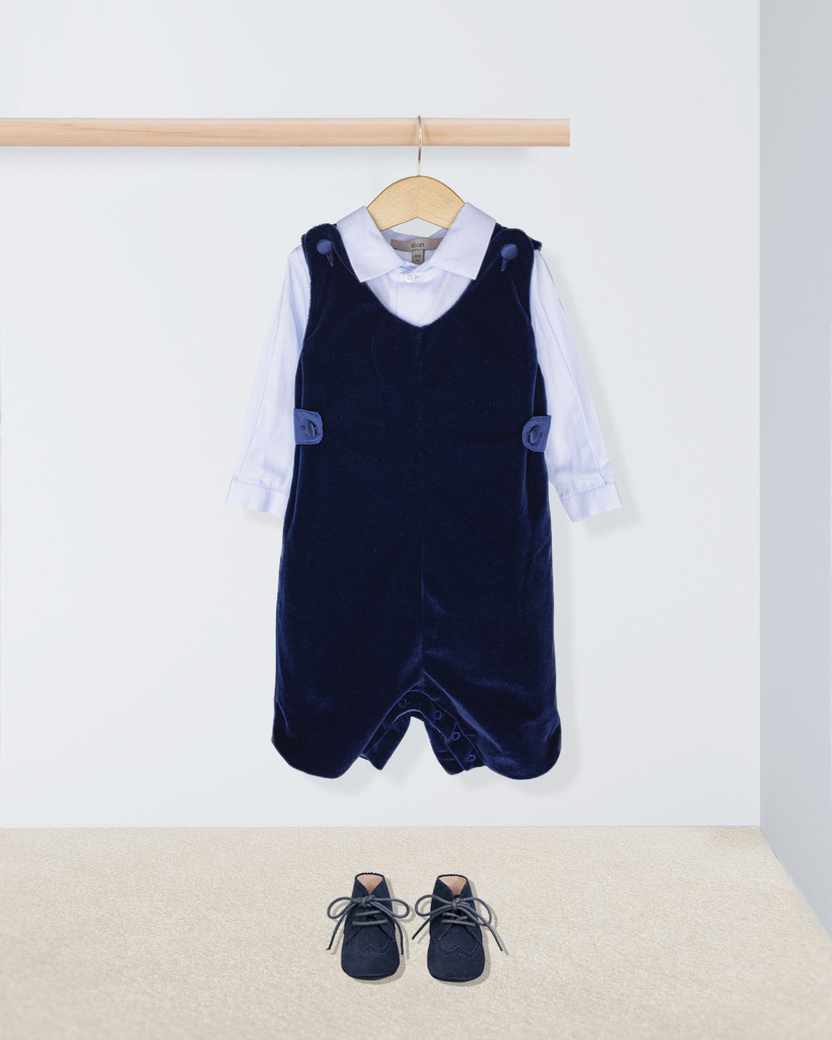 Navy blue velvet pinafore with white shirt and shoes on a light background