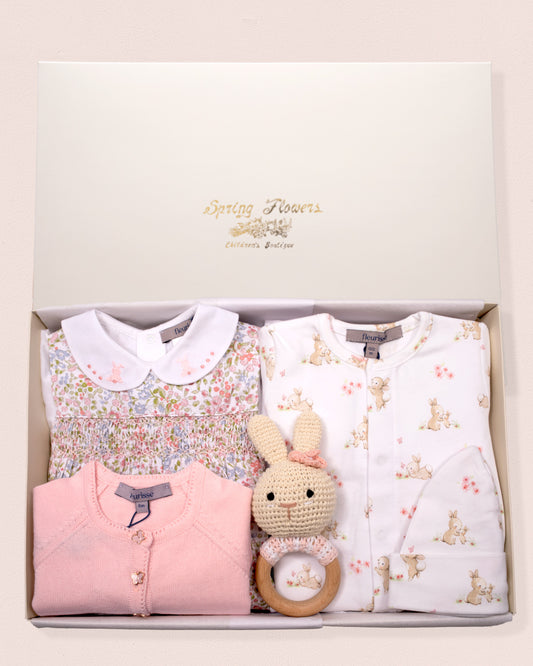 Baby gift set with floral top, pink outfit, and bunny rattle in a box.