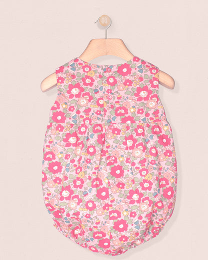 Floral patterned baby sleeping bag on a hanger against a beige background