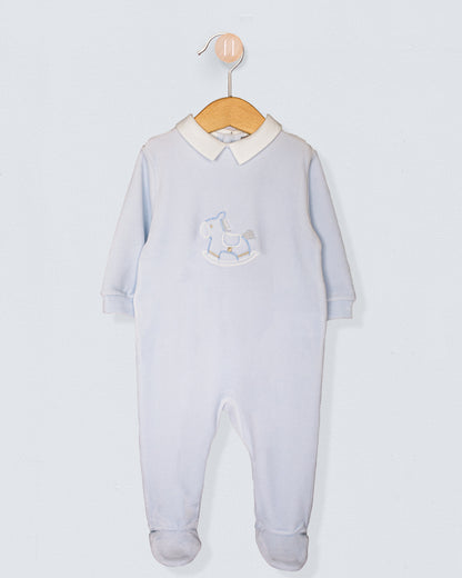Light blue baby footie made of soft Italian velour, with long sleeves and an embroidered blue rocking horse on the chest, hung on a wood hanger.