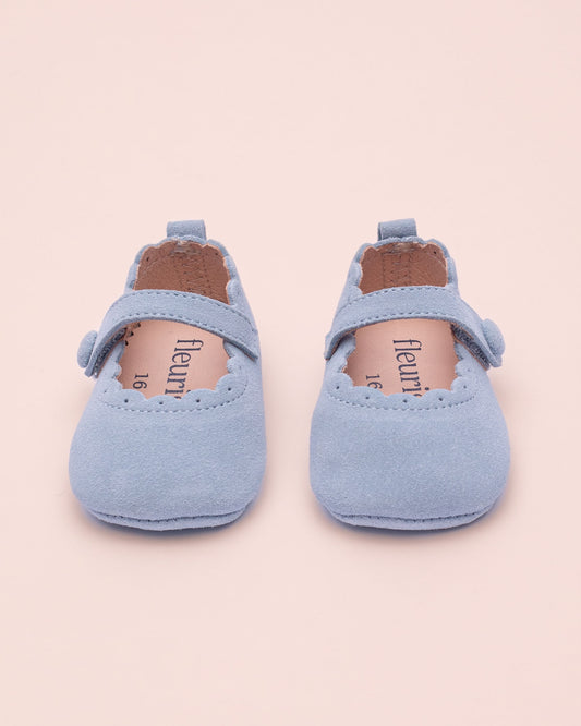 Pair of light blue baby shoes on a beige background