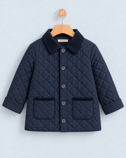 A navy blue quilted jacket for toddlers, featuring a corduroy collar, button-front closure, and two front patch pockets, hanging on a wooden hanger against a light gray background.