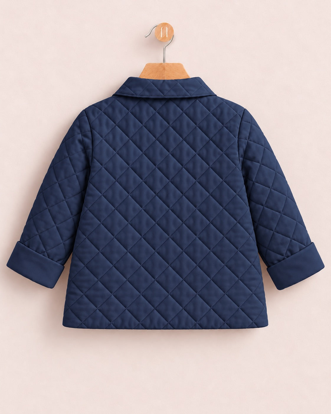 A navy blue quilted jacket with a pointed collar and three-quarter sleeves, shown from the back on a wooden hanger against a light pink background.