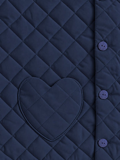 Close-up of a quilted navy jacket or vest with a heart-shaped patch pocket and matching buttons on the side.