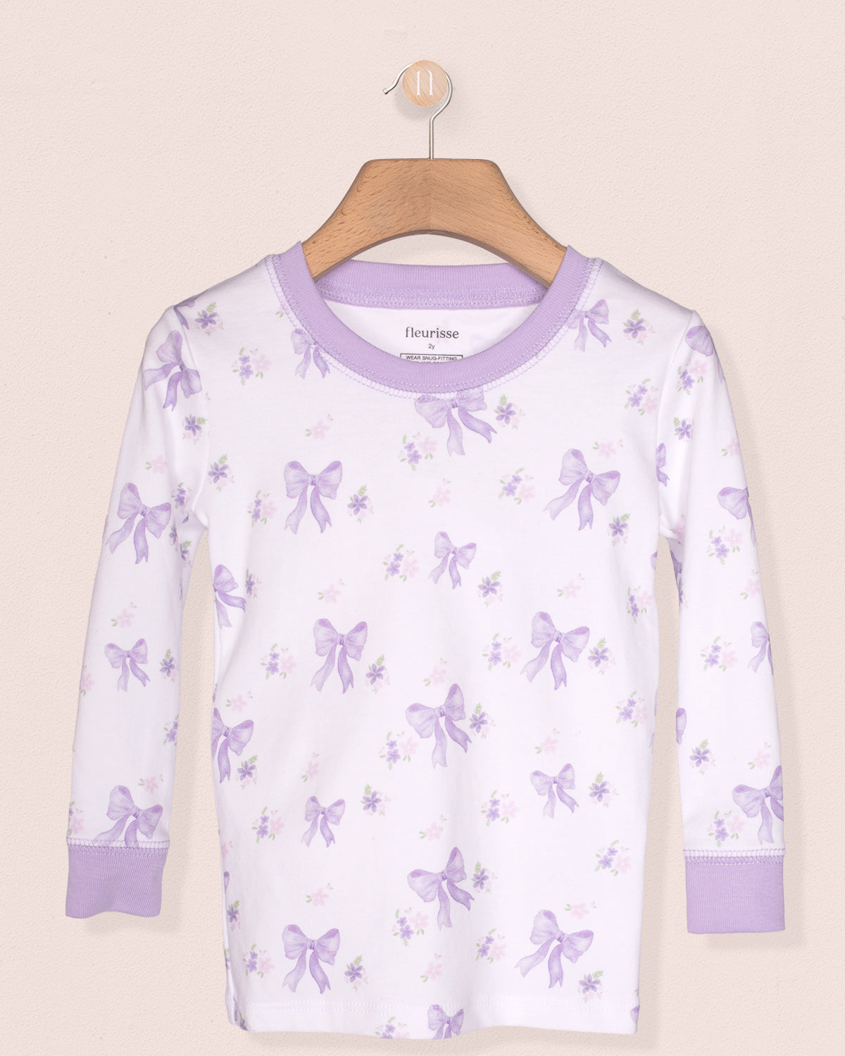 White long-sleeve shirt with purple butterfly pattern on a hanger against a beige background