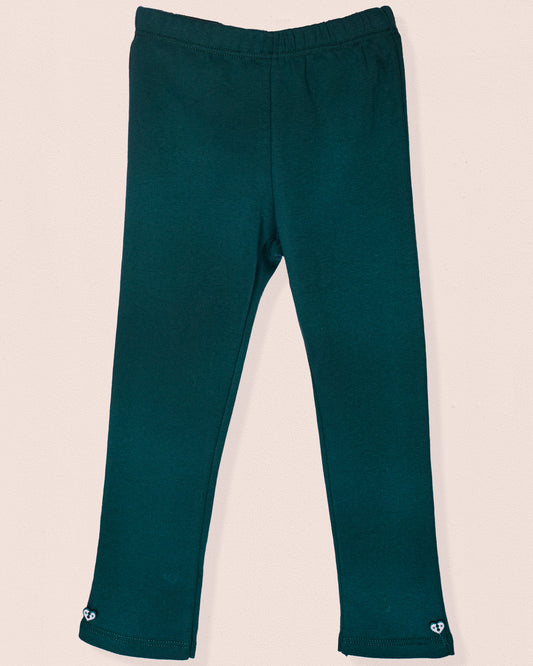 A pair of hunter green brushed cotton leggings displayed flat against a light beige background. The leggings feature a smooth elastic waistband and small heart-shaped button details at the ankle cuffs. Made from soft Italian jersey with a cozy brushed interior.