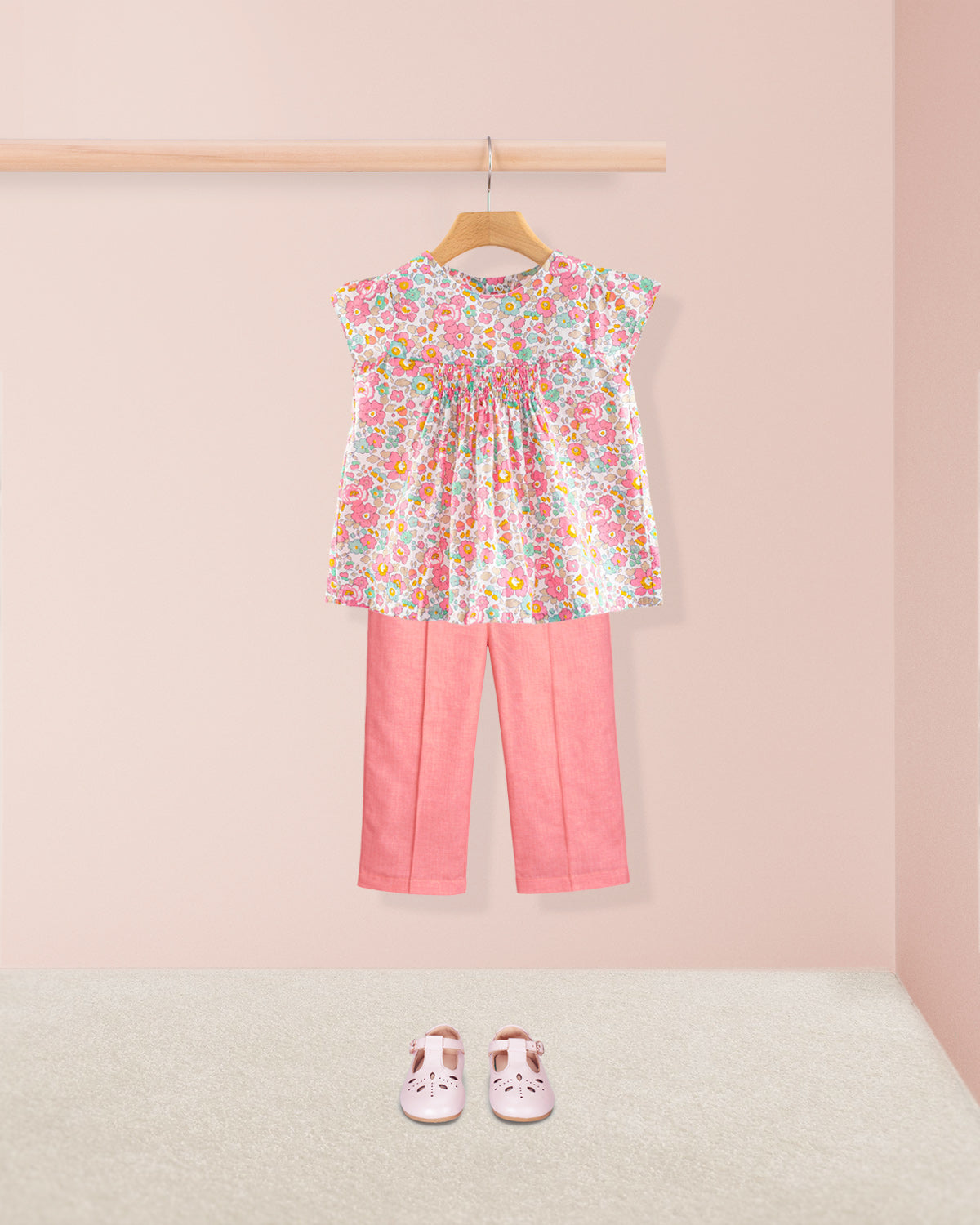 Floral top and pink pants with shoes on a light pink background