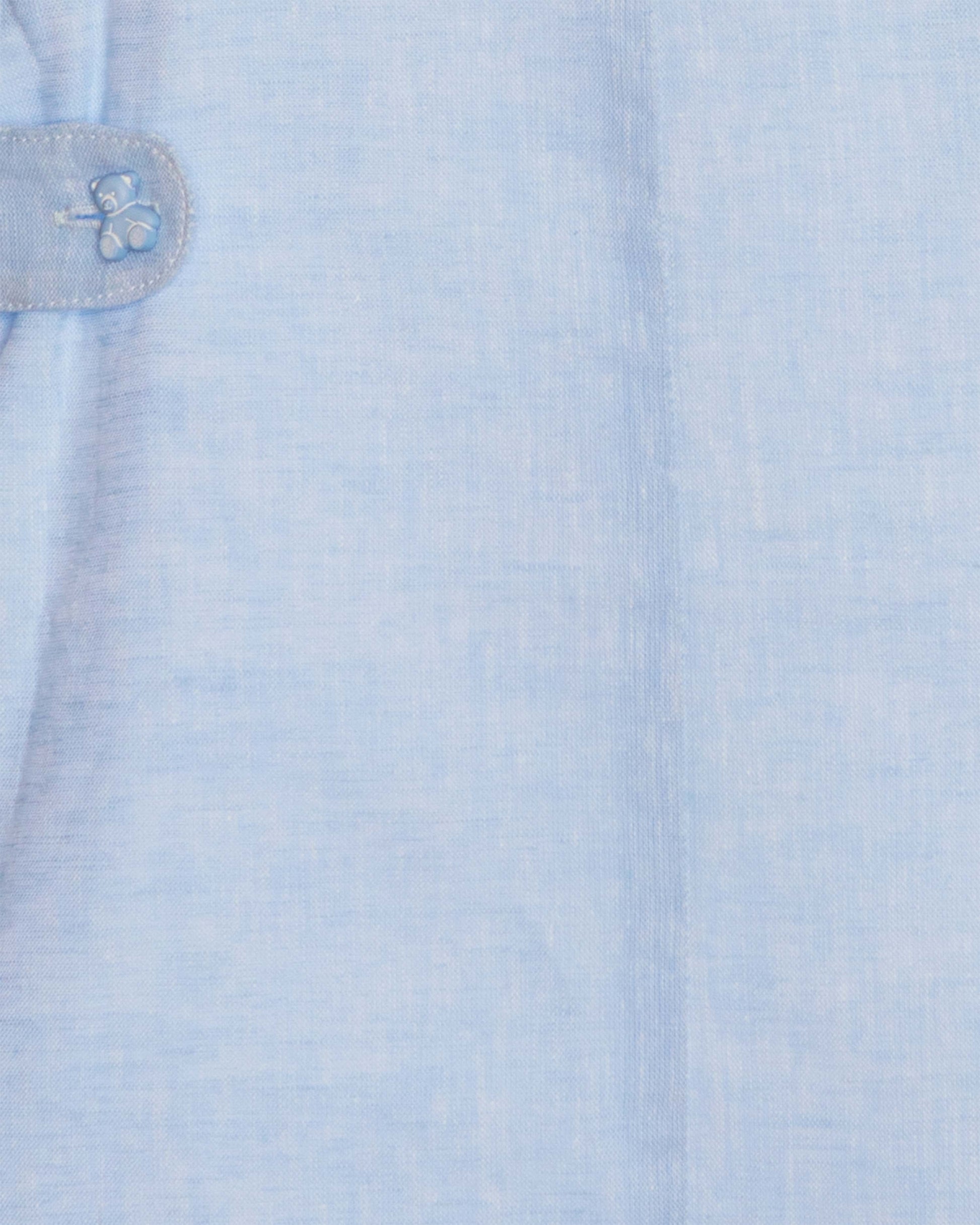 Close-up of a light blue shortall with a teddy bear button detail.