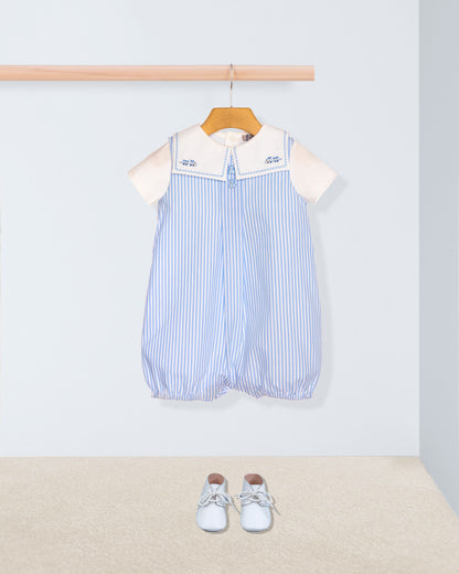 Baby romper with striped pattern and white collar on a hanger, with baby shoes on the floor.