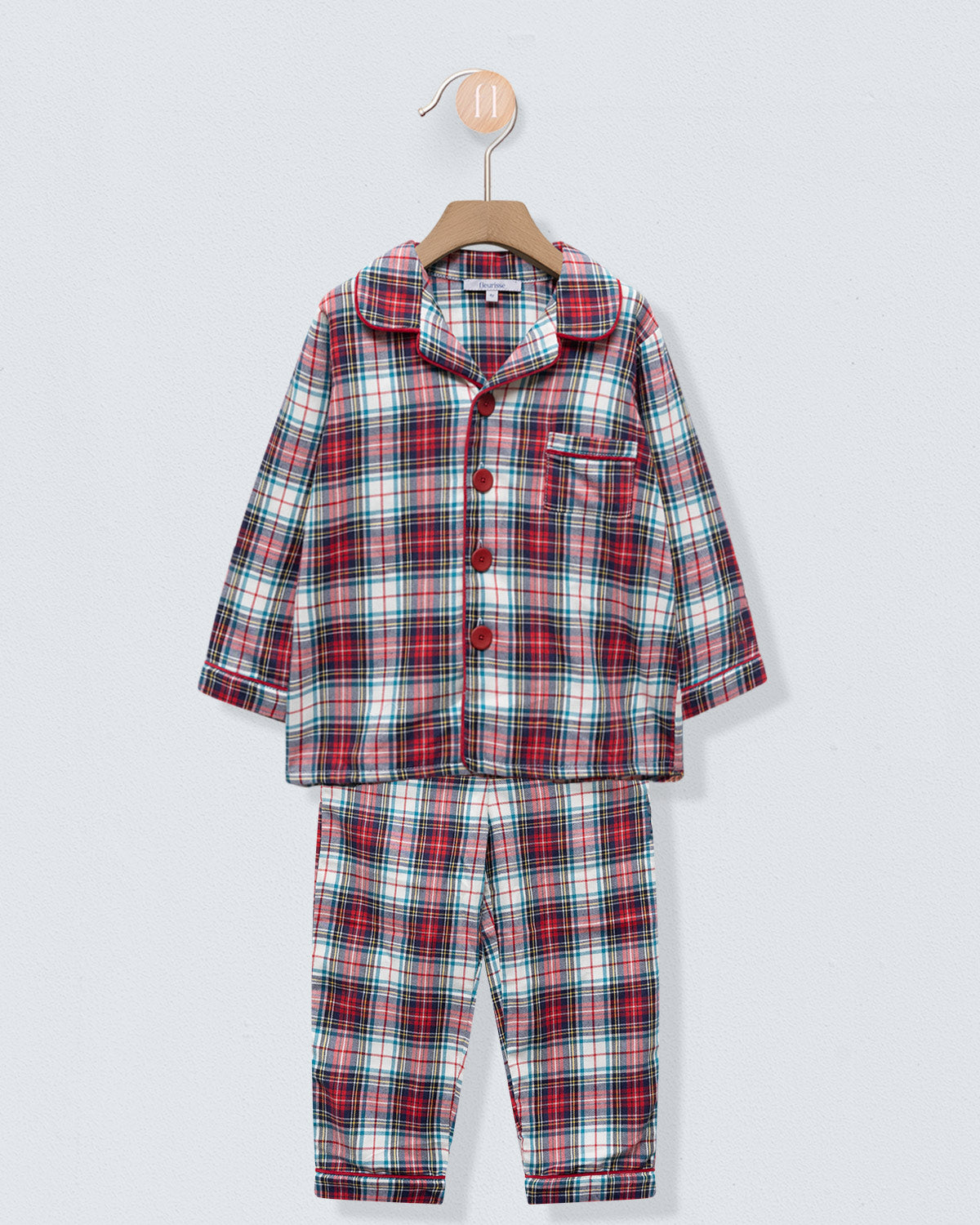 Plaid pajama set on a hanger against a light gray background