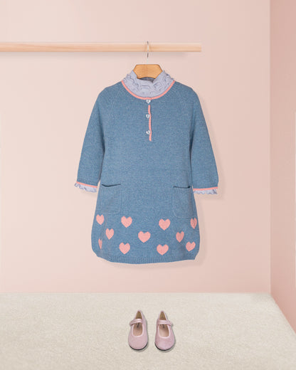 Blue dress with pink heart patterns and matching shoes on a pink background