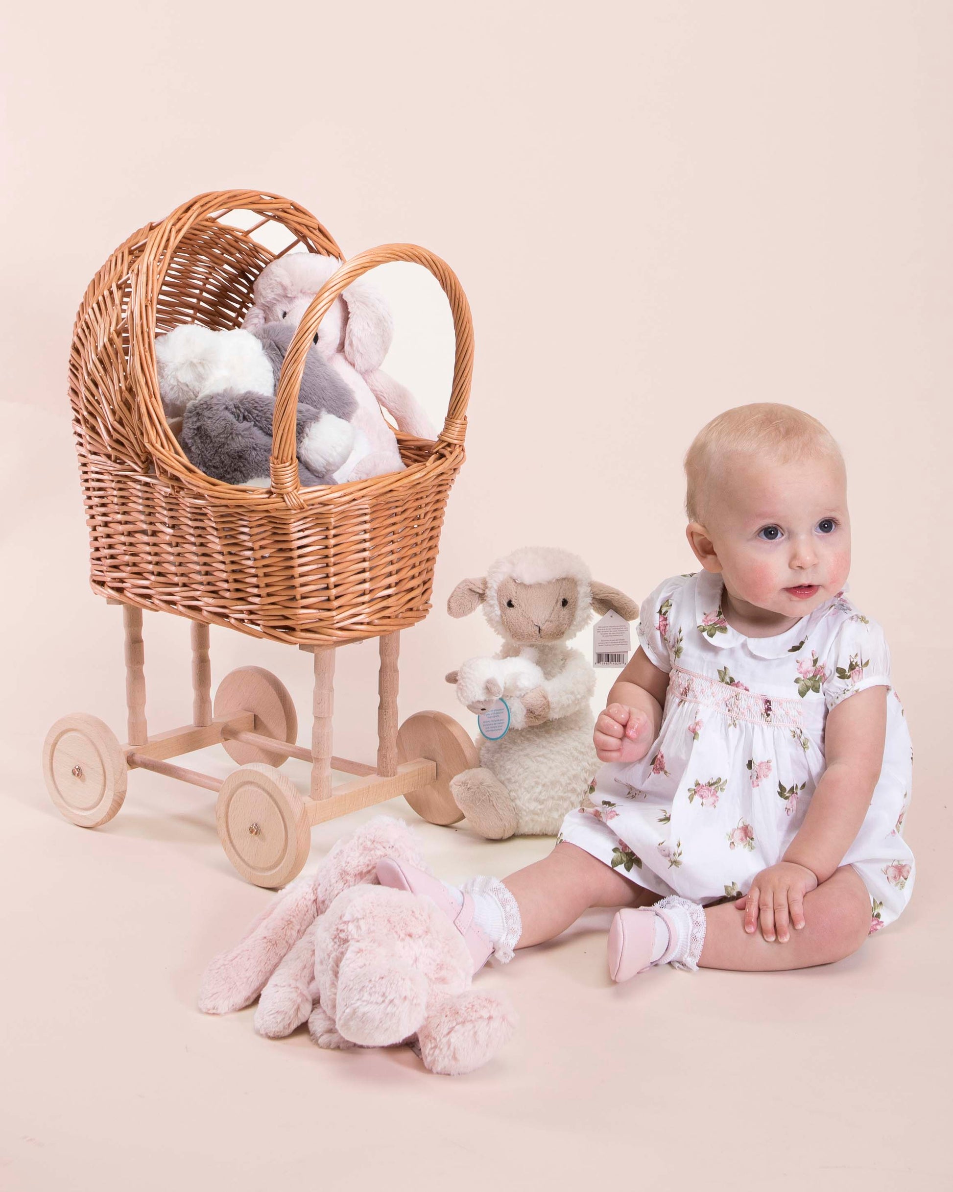 Baby girl sitting on the floor surrounded by Jellycat toys wearing Baby Madeline Delicate Rose Dress and Diaper Cover 