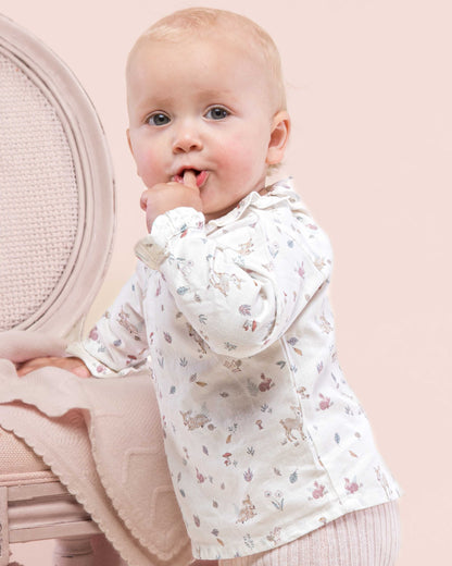 Baby model girl wearing Minette Pink Fawn Tunic facing to the side looking to the front showing the side of the tunic