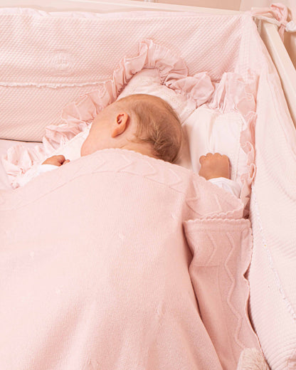 Baby sleeping on a crib with Cherie Cashmere Pink Blanket, showing the details and trimmings of the blanket