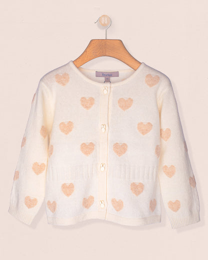 White cardigan with pink heart patterns on a wooden hanger against a light background