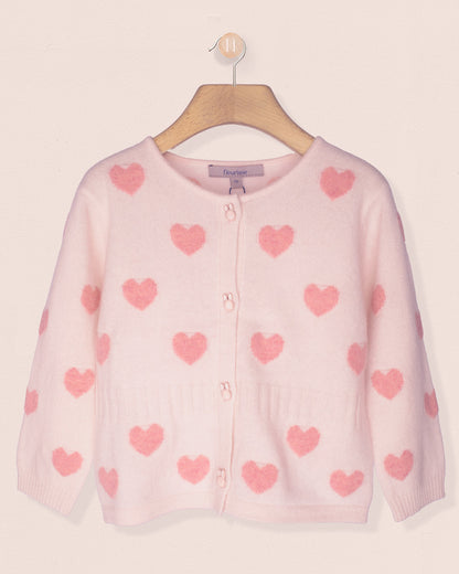 Pink cardigan with heart patterns on a hanger against a light pink background