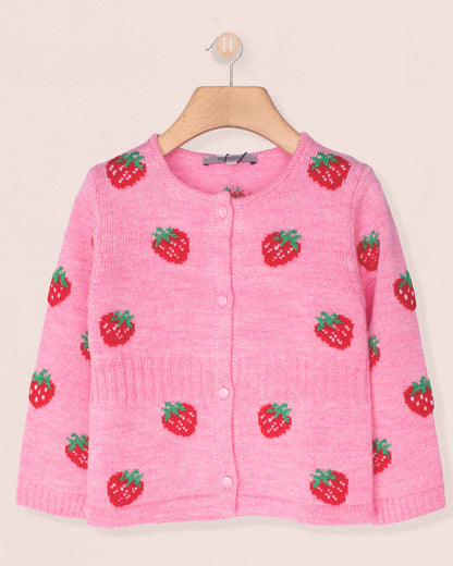 Pink knitted cardigan with strawberry pattern on a hanger against a light pink background