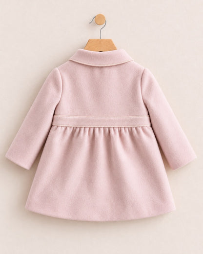 Backside of a light pink coat with a waist band, on a hanger against a muted pink background
