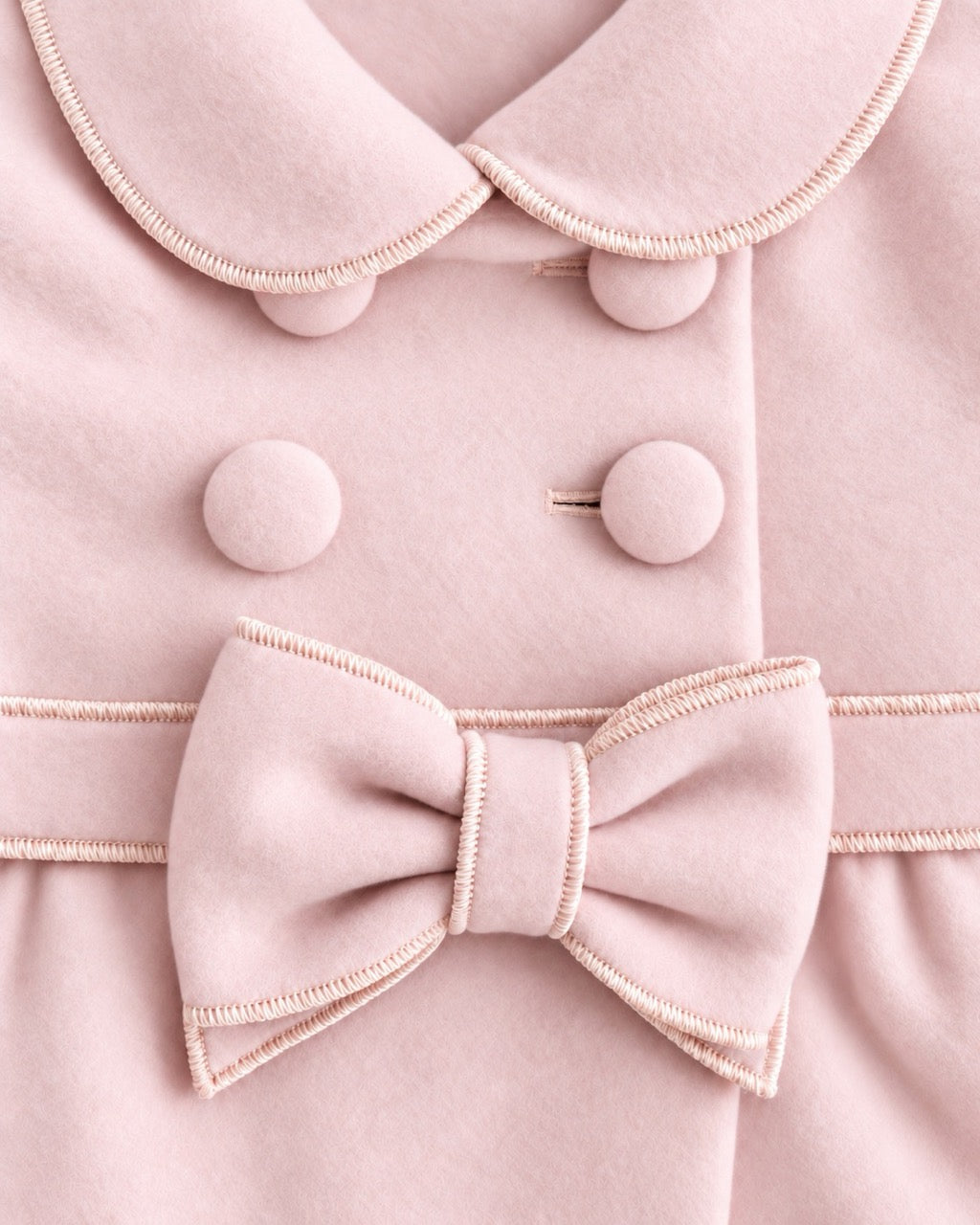 closeup of Light-pink colored coat with 4 buttons, collars and a large pink bow