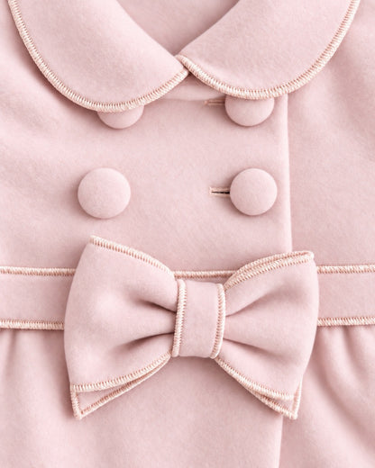 closeup of Light-pink colored coat with 4 buttons, collars and a large pink bow