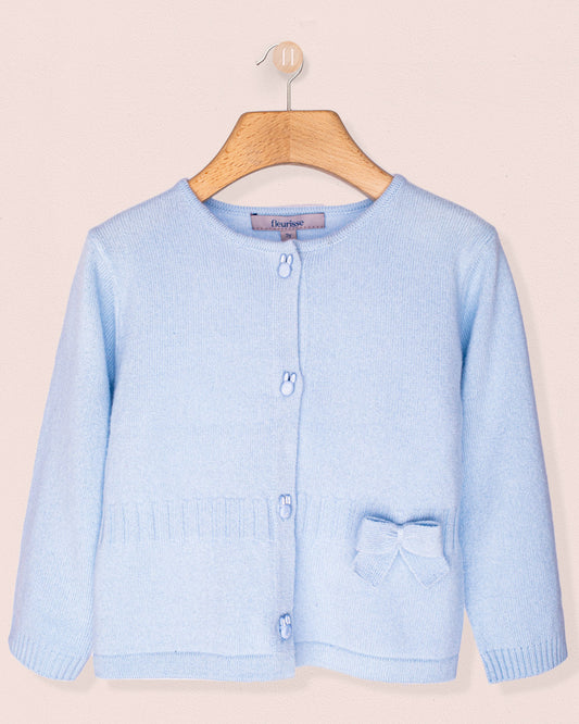 Light blue cardigan with a bow and bunny buttons, on a wooden hanger against a beige background