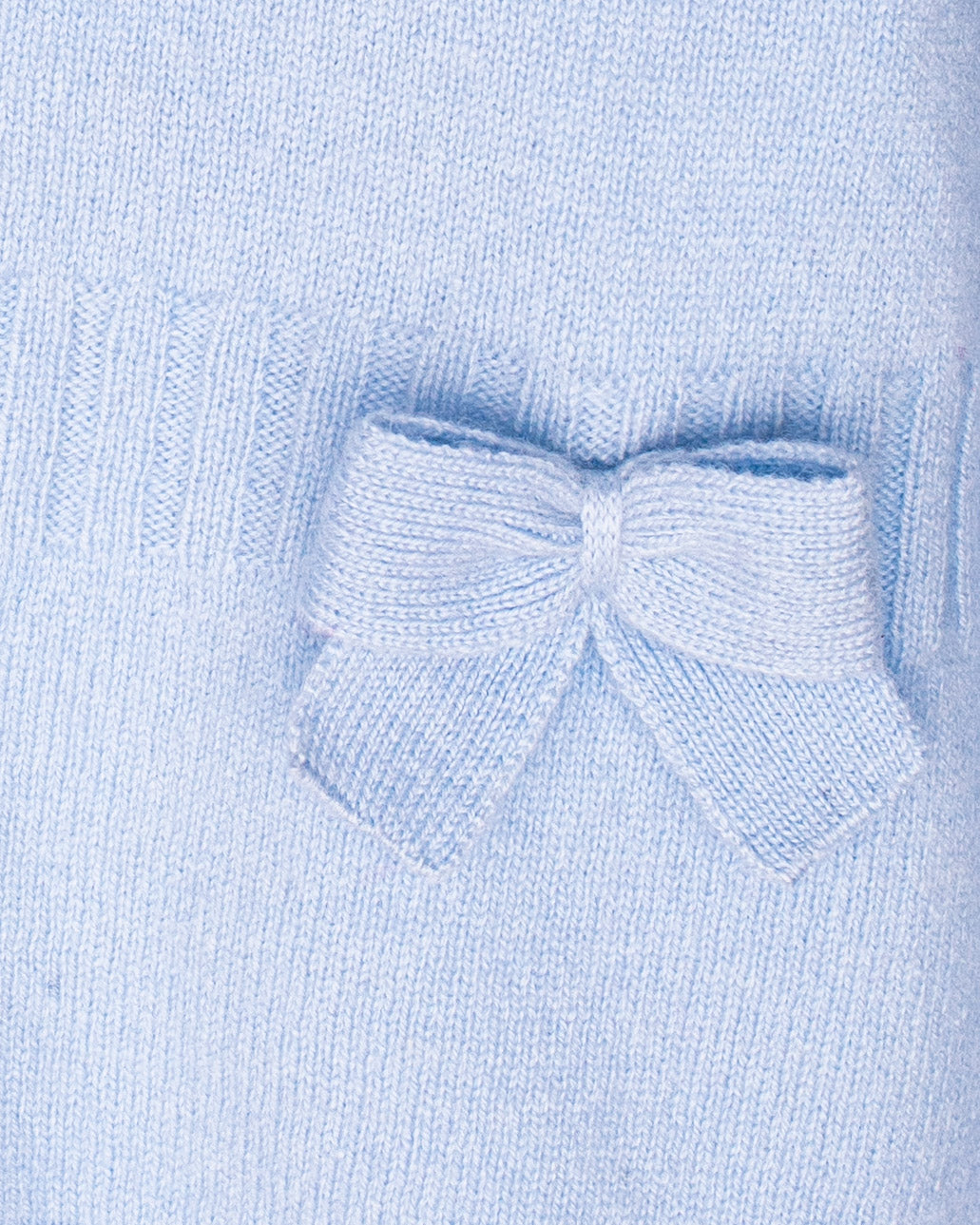 Close-up of a light blue knitted sweater with a bow detail.