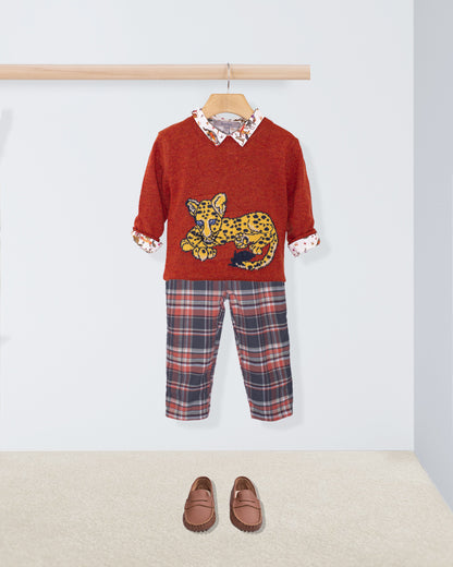 Children's outfit with red sweater featuring a leopard design, plaid pants, and brown shoes on a white background.