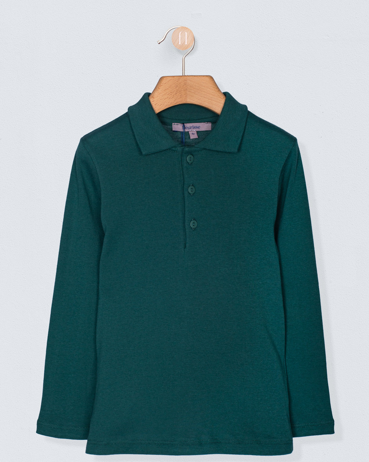 Long-sleeve brushed cotton polo shirt in hunter green, shown hanging on a wooden hanger against a light background. Features a classic polo collar and three-button placket.