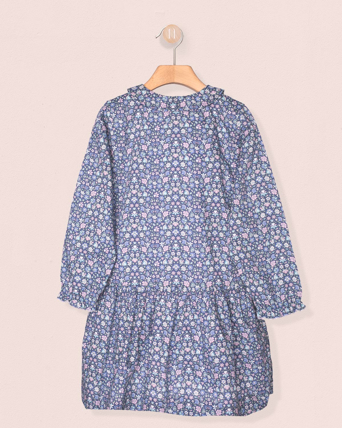 Blue floral dress on a hanger against a light pink background