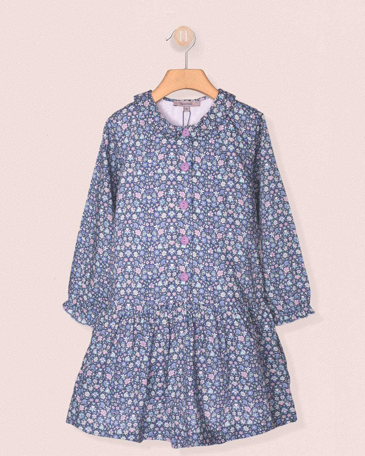 Blue floral dress on a hanger against a beige background