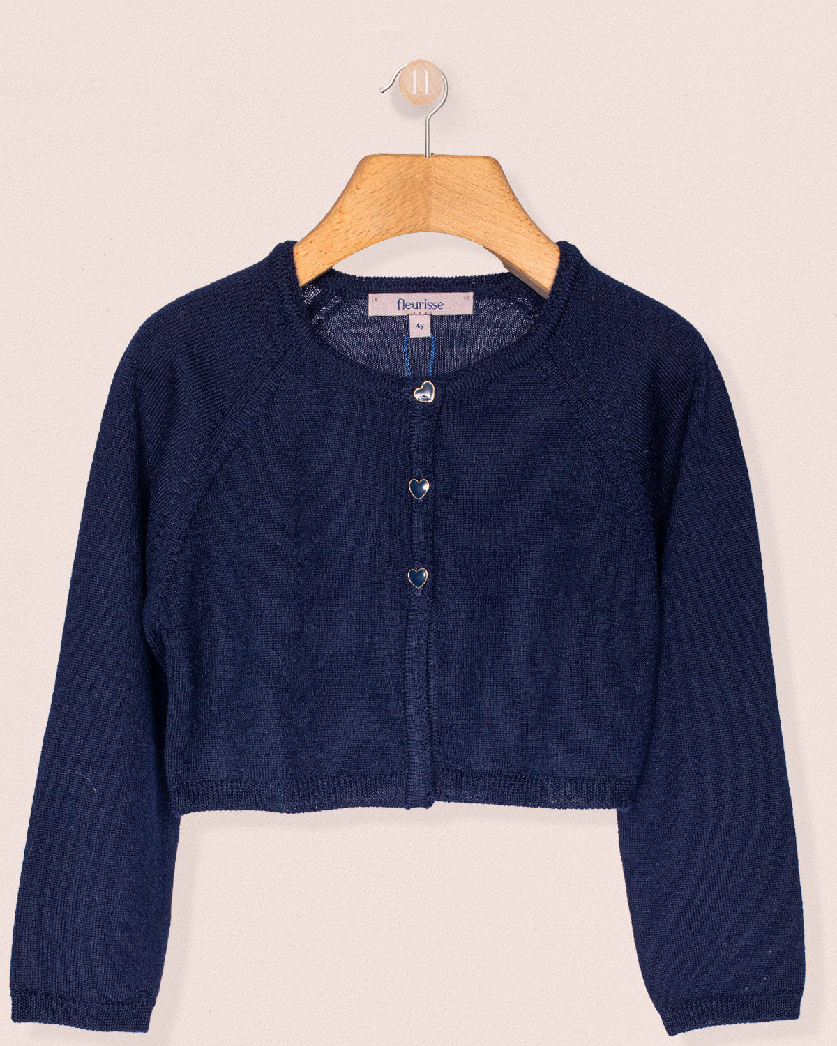 Navy blue cardigan on a wooden hanger against a beige background
