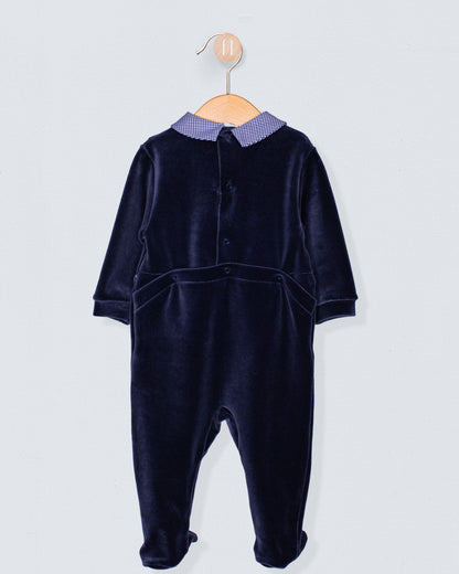 Back view of navy Italian velour footie featuring discreet snap closures along the panel seam and upper back, displayed on wooden hanger.