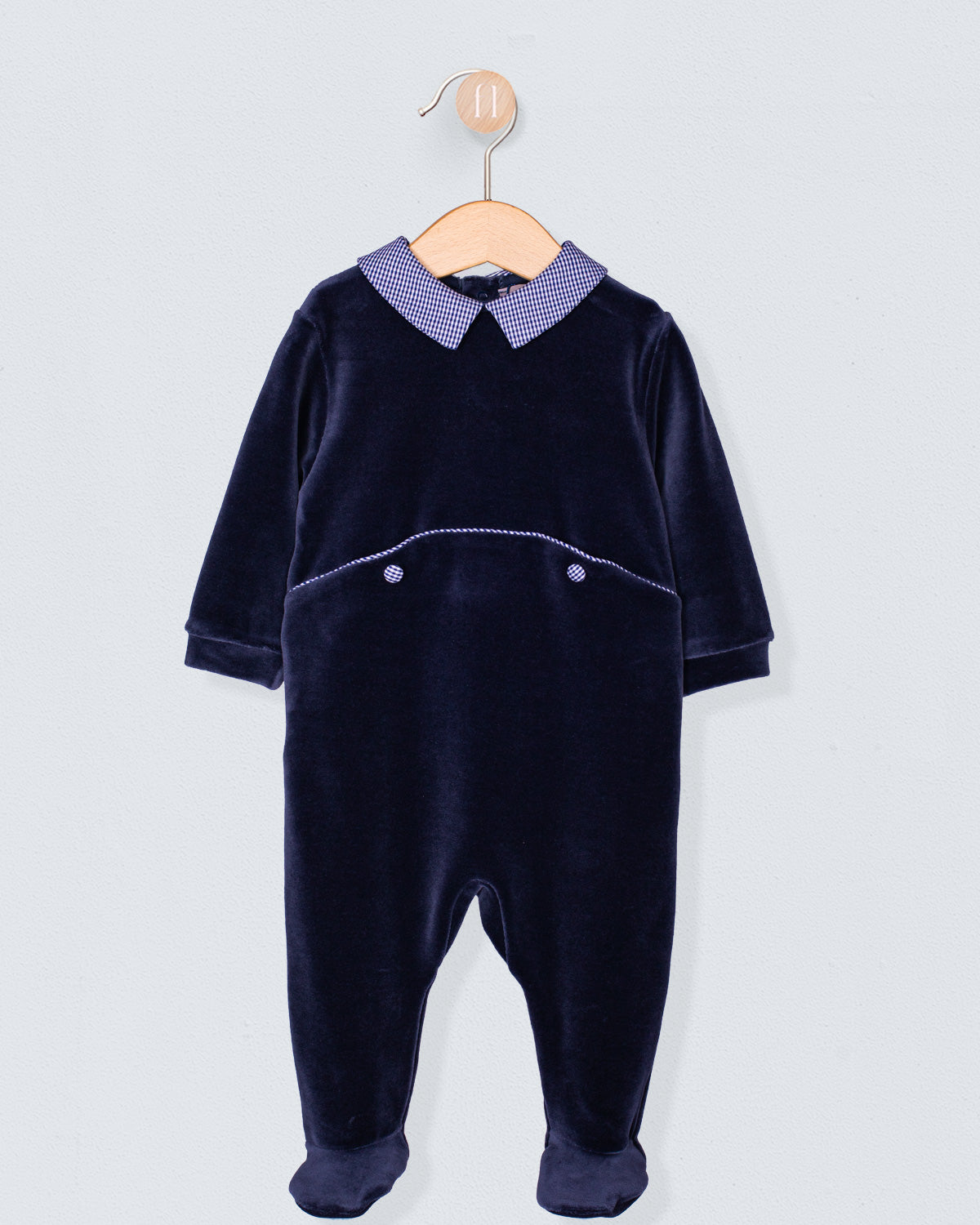 Navy Italian velour footie with a blue gingham Peter Pan collar and decorative pocket seam detail, displayed on wooden hanger.