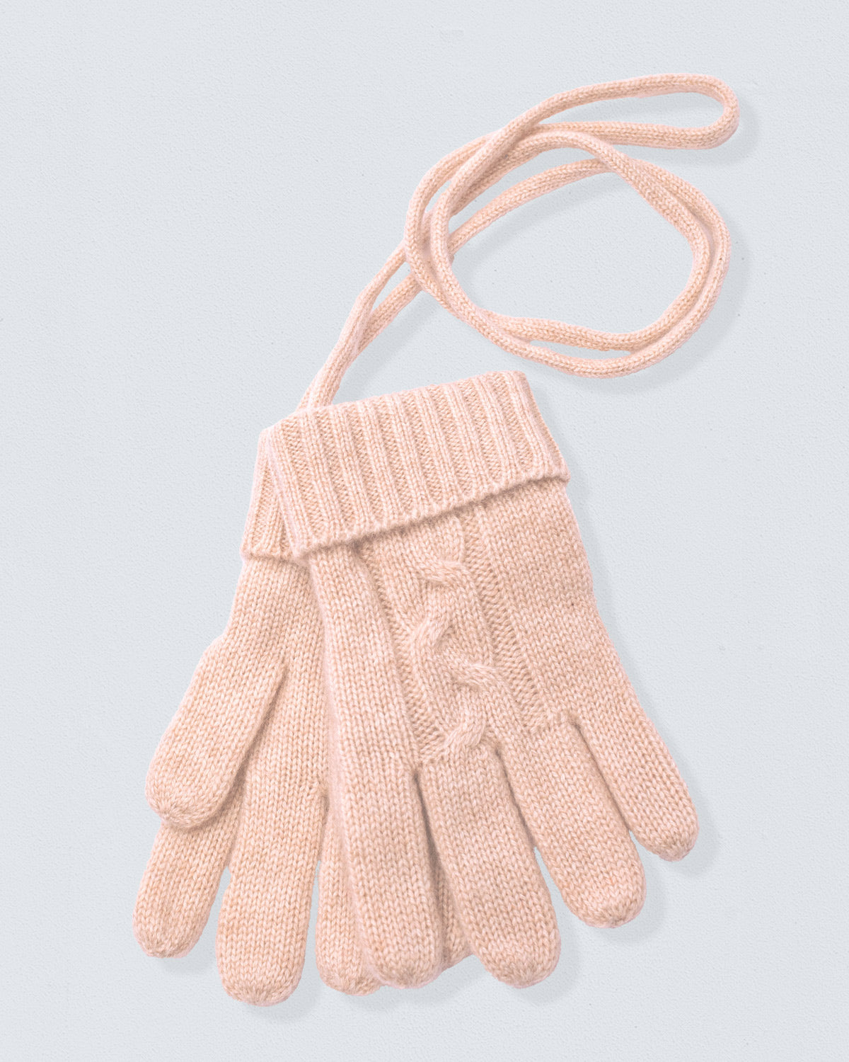 Pair of beige gloves with a cable knit pattern on a light gray background