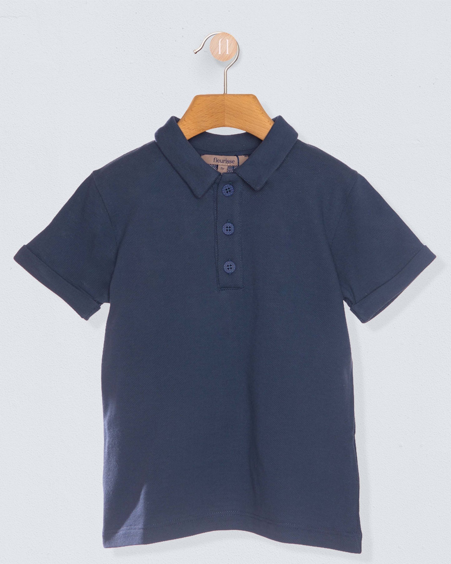 navy polo shirt on hanger against light blue grey background