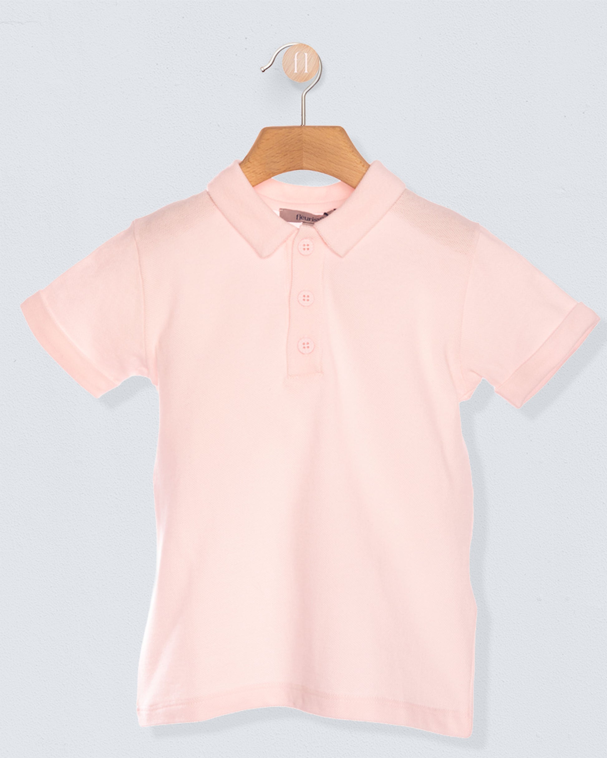 Pink polo shirt on a hanger against a light gray background