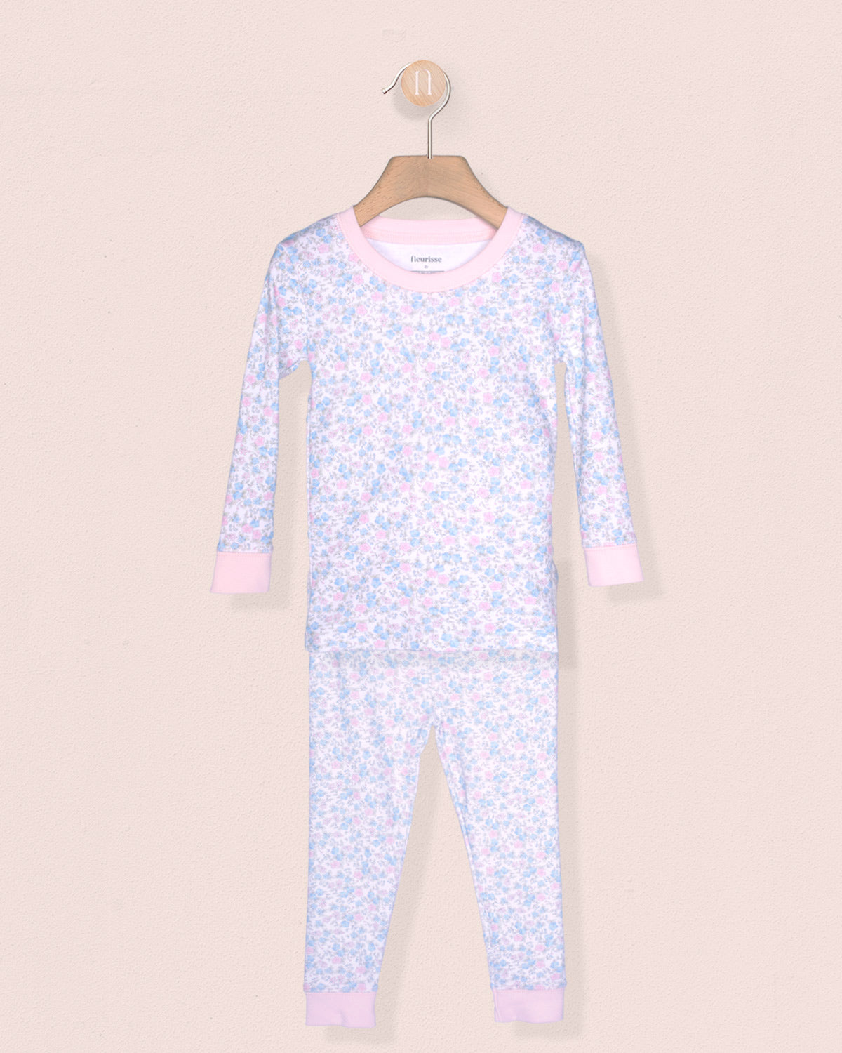 Floral-patterned onesie on a hanger against a beige background