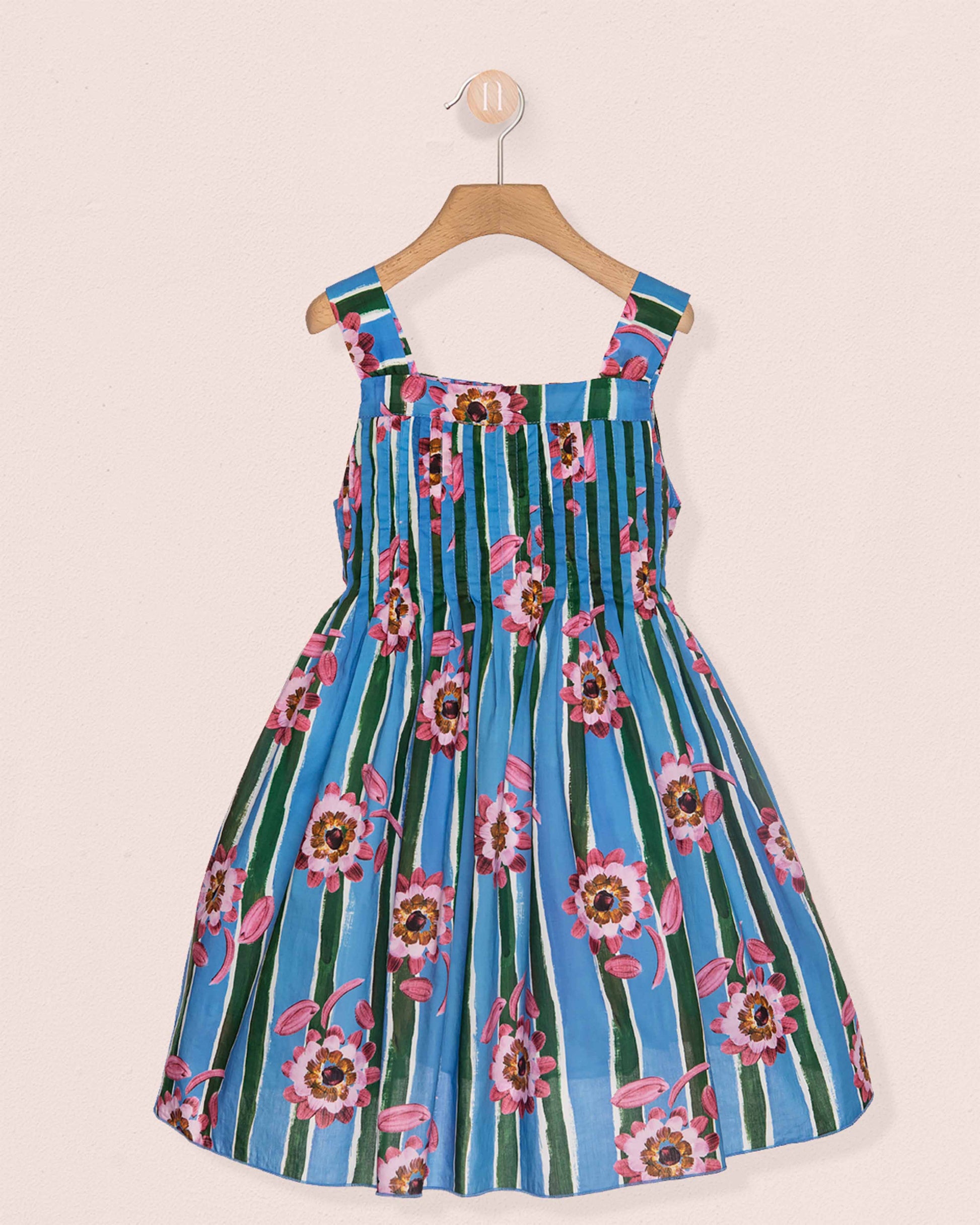 Floral and striped dress on a hanger against a beige background