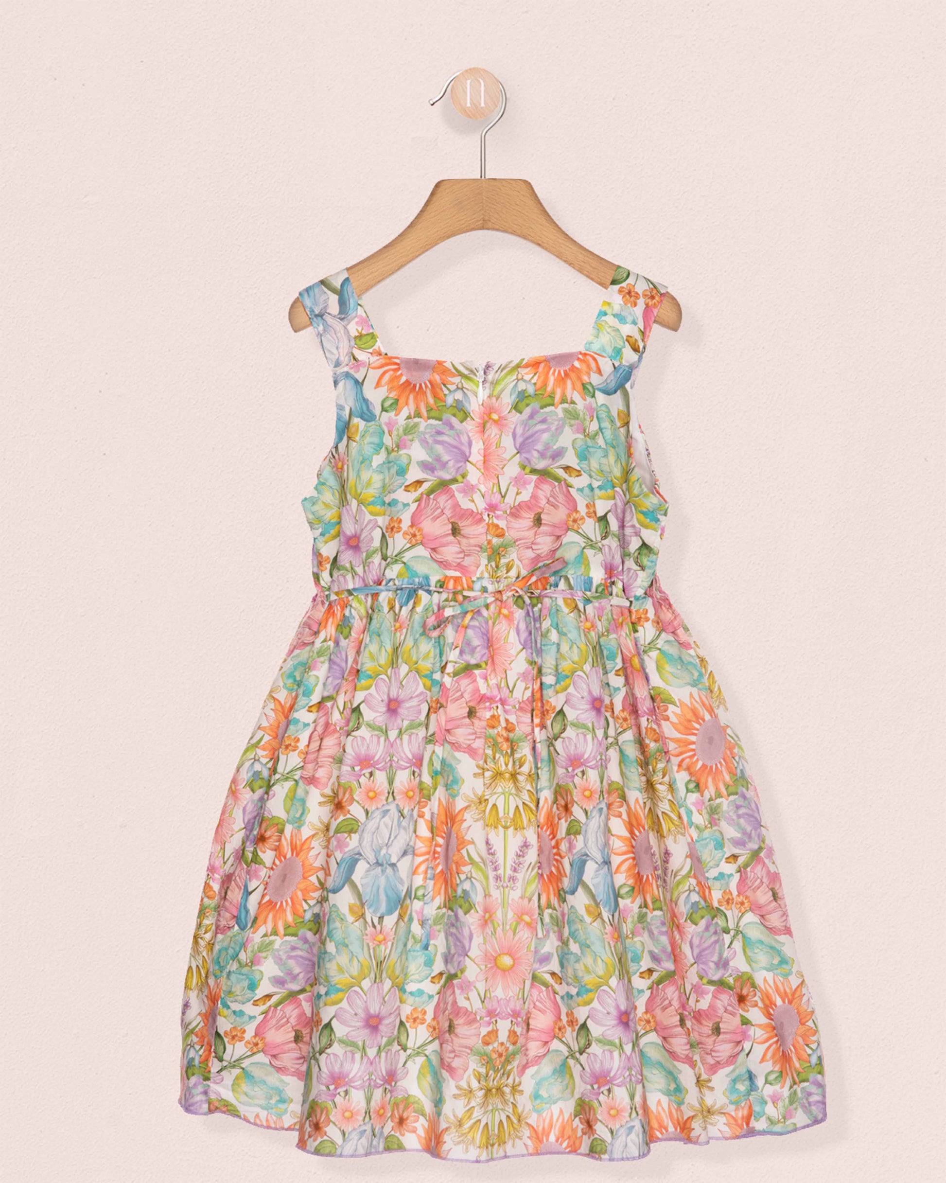 Floral dress on a hanger against a light pink background