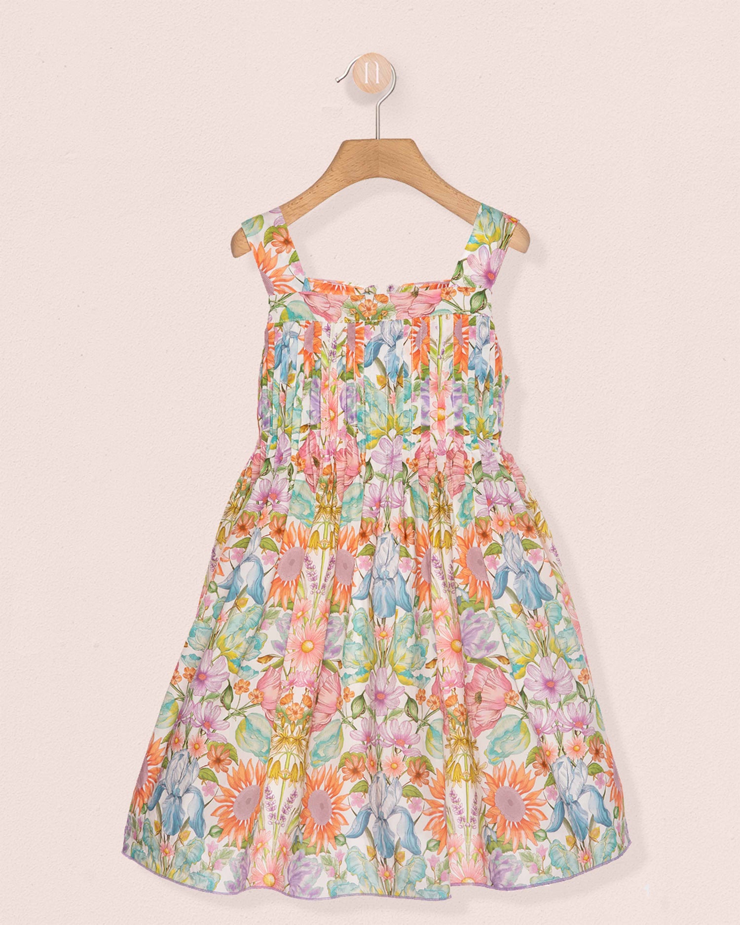 Colorful floral dress on a hanger against a light background