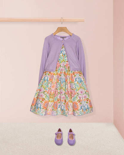 Children's dress with floral pattern and long-sleeve top on a hanger against a pink wall.