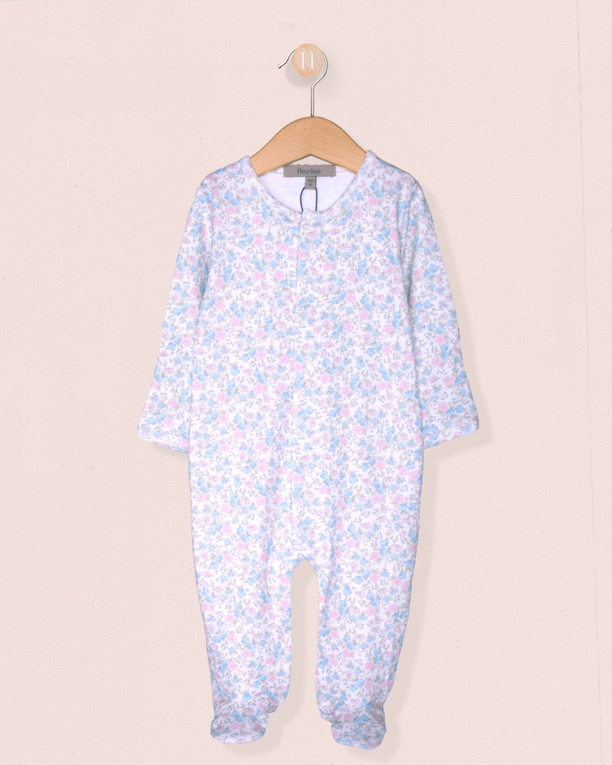 Floral-patterned baby onesie on a hanger against a beige background