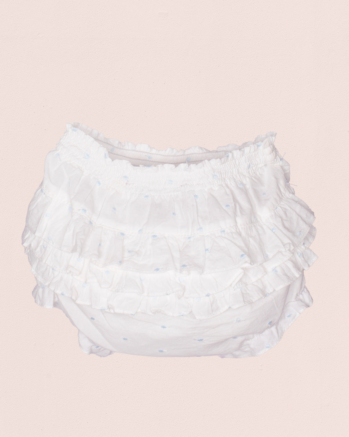White ruffled diaper on a light pink background