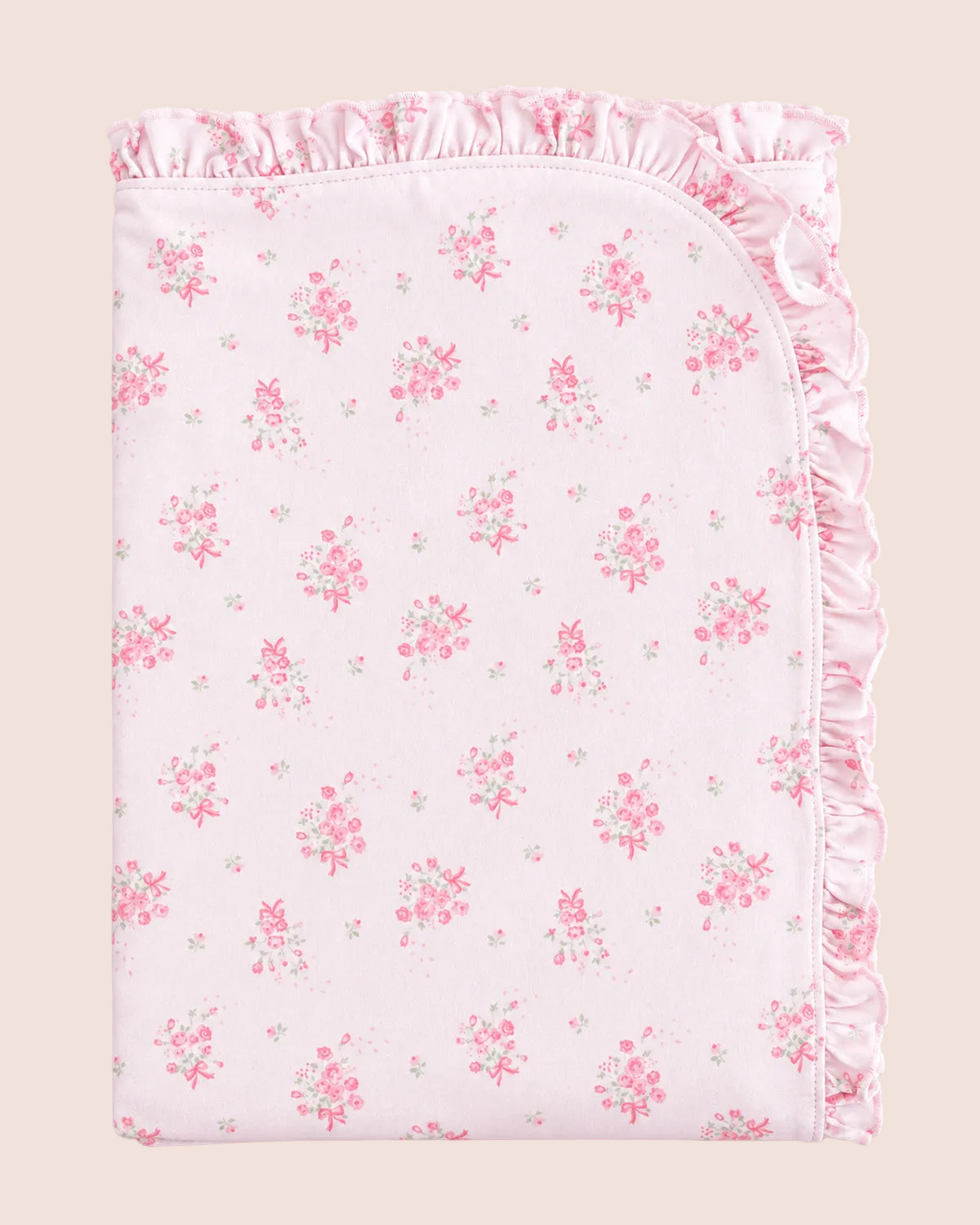 A folded baby blanket or swaddle with a light pink background, featuring a delicate pink and green floral pattern and a ruffled satin border, set against a solid pale pink background.