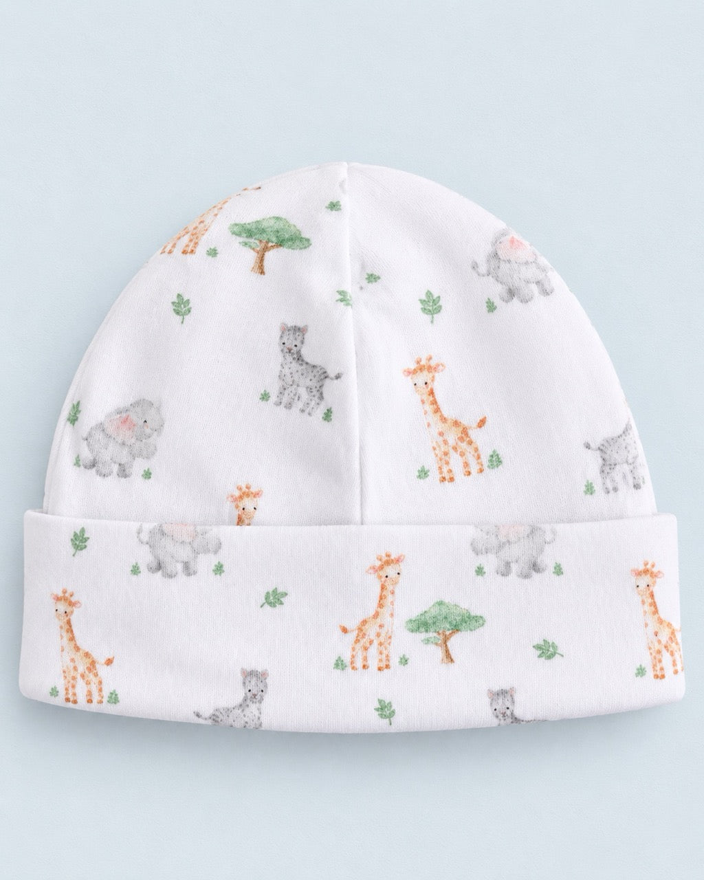A white knit baby beanie hat featuring a cute safari animal print with giraffes, elephants, and trees, set against a light blue background.